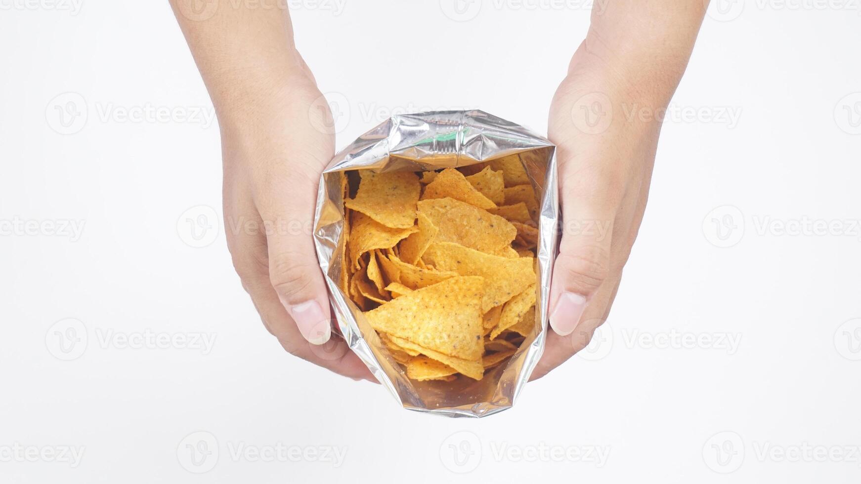 Man hands with an opened foil bag of yellow tortilla chips isolated on white background photo