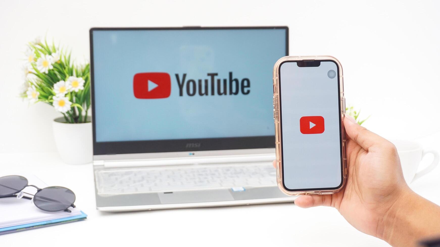 Yogyakarta, Indonesia, 2025 - Hand holding smartphone that shows icon of Youtube platform application on the screen isolated on white background photo