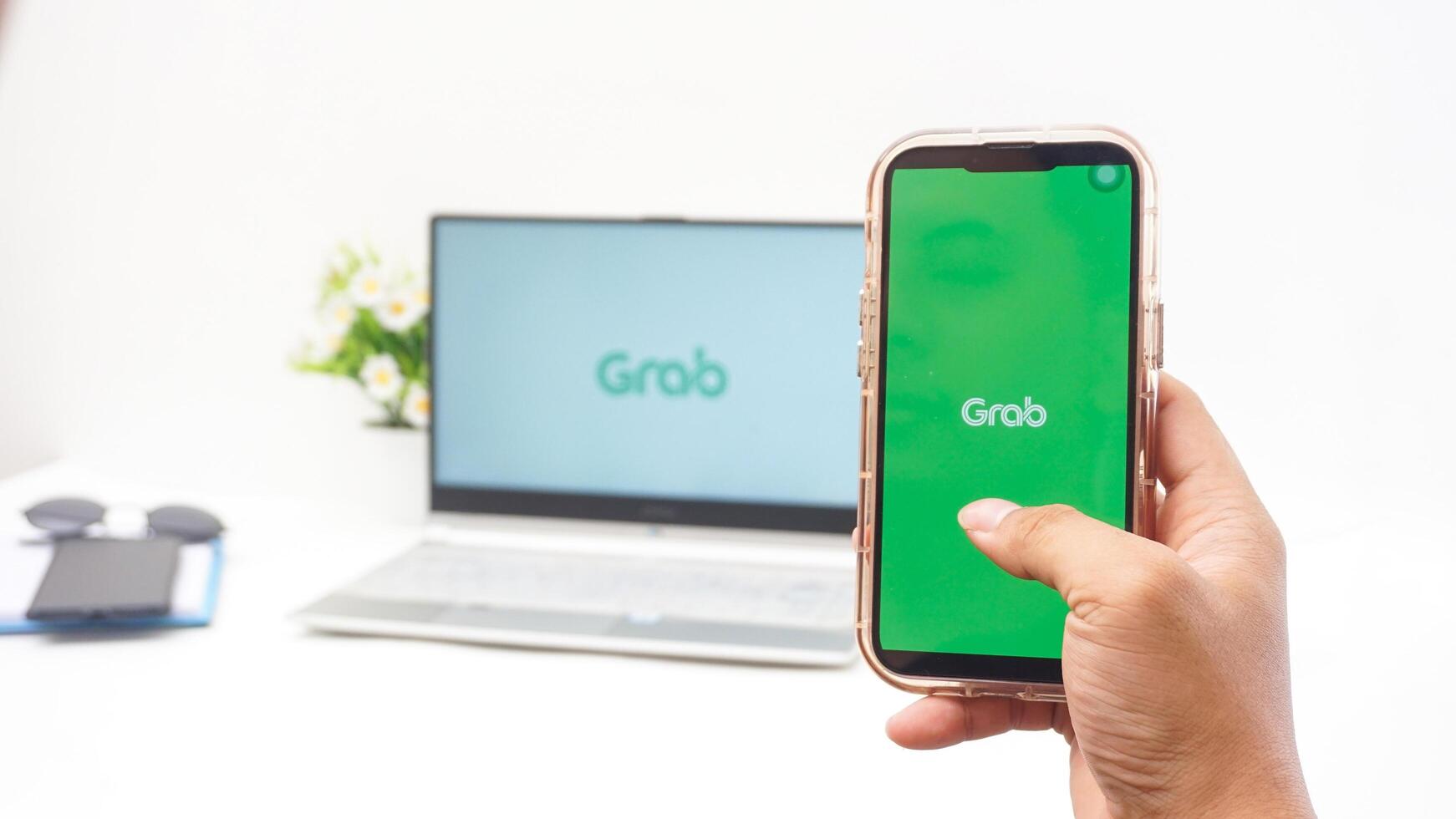 Yogyakarta, Indonesia, 2025 -Man hand with smartphone that shows front page of Grab application, on-demand service platforms from Indonesia, on the screen isolated on white background photo