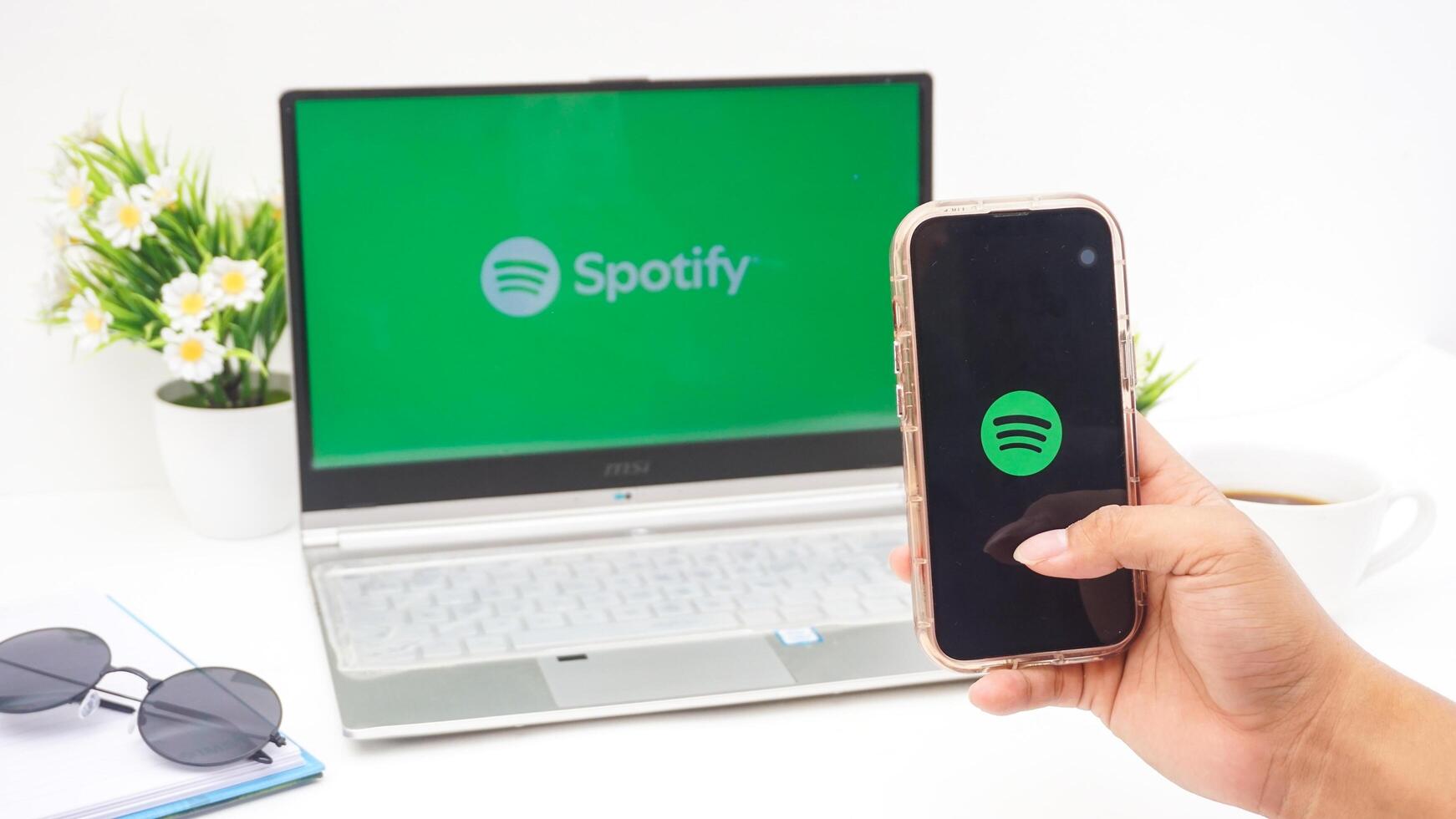 Yogyakarta, Indonesia, 2025 - Hand holding smartphone that shows front page of Spotify, digital audio streaming platform application on the screen isolated on white background photo