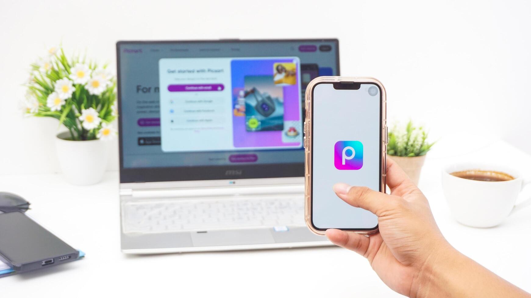 Yogyakarta, Indonesia, 2025 - Man hand holding smartphone that shows front page of Picsart, a creative editing platform application on the screen isolated on white background photo