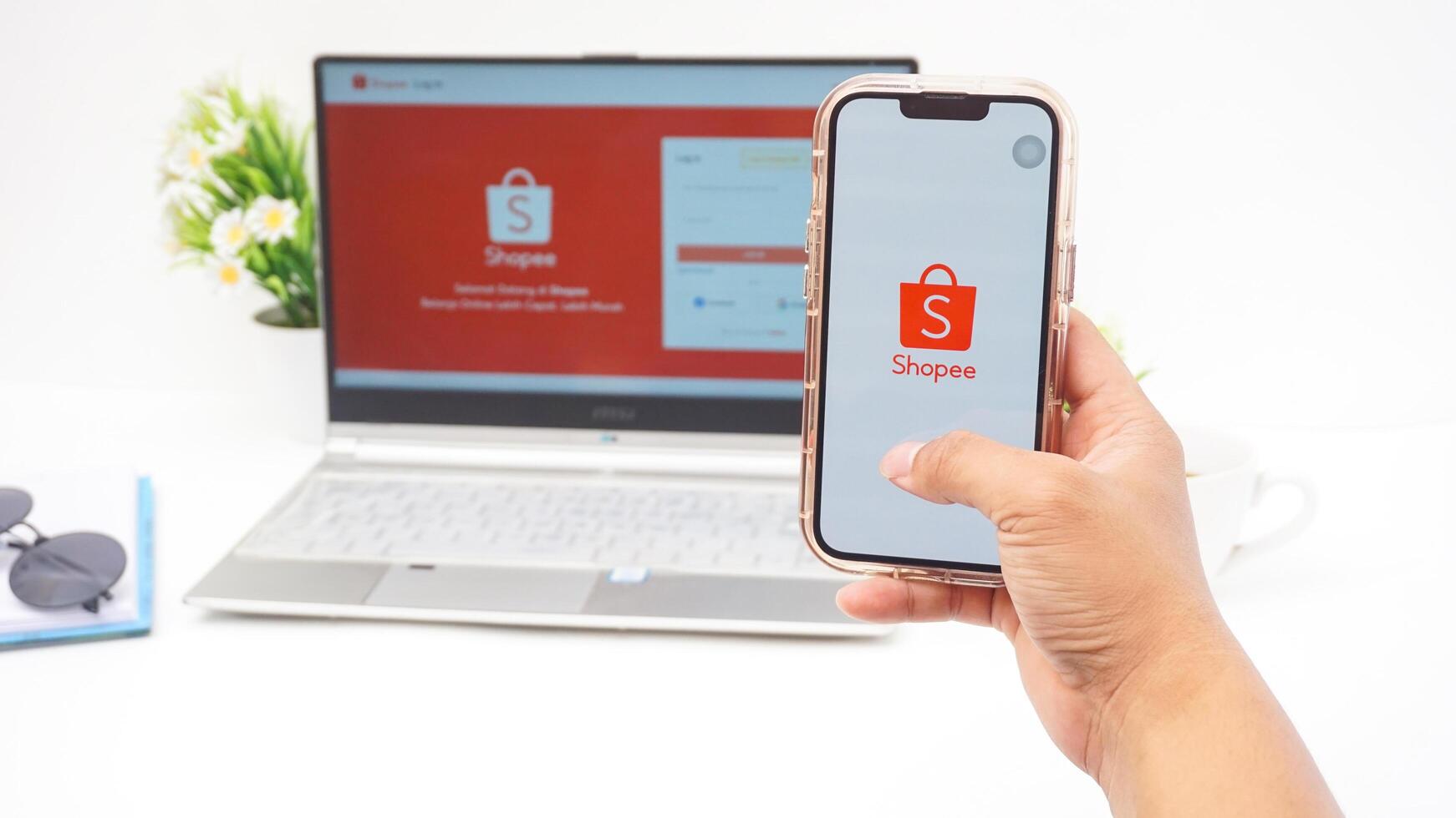 Yogyakarta, Indonesia, 2025 - Hand using smartphone that shows front page of Shopee, e-commerce or online shopping platform application on the screen isolated on white background photo