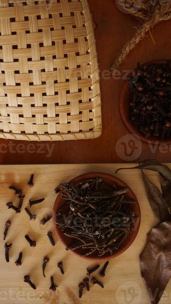 Top view of cloves spice on wooden platters isolated on wooden texture background photo