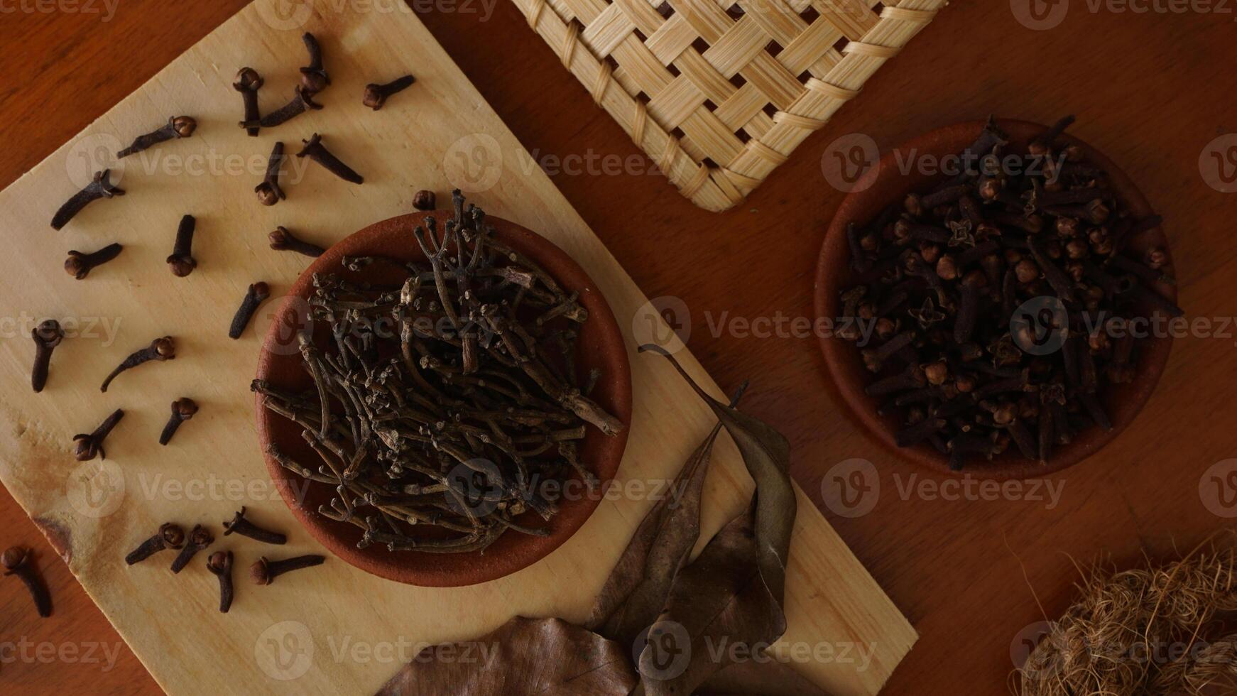 Top view of cloves spice on wooden platters isolated against wooden texture background photo