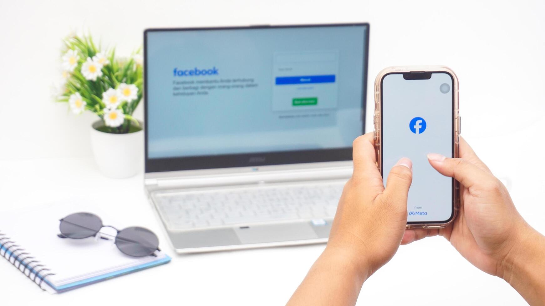 Yogyakarta, Indonesia, 2025 -Man hand using smartphone that shows front page of Facebook, social networking service application on the screen isolated on white background photo