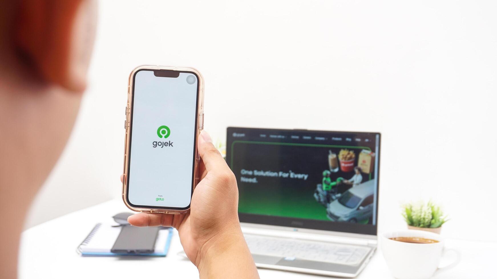 Yogyakarta, Indonesia, 2025 -Man using smartphone that shows front page of Gojek application, on-demand service platforms from Indonesia, on the screen isolated on white background photo