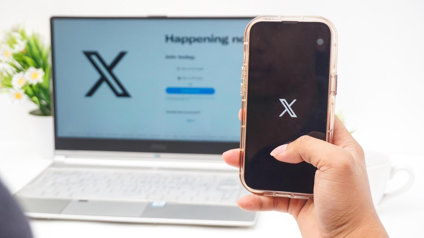 Yogyakarta, Indonesia, 2025 - Hand holding smartphone that shows front page of X application former Twitter, social media platform on the screen isolated on white background photo