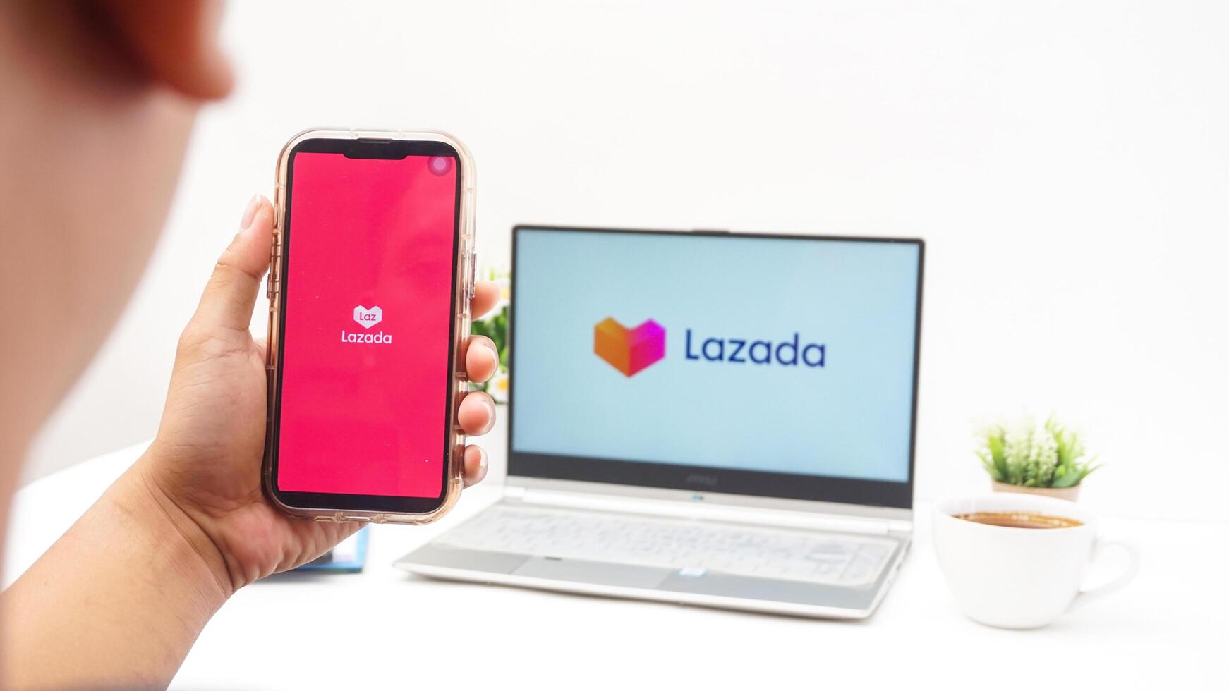 Yogyakarta, Indonesia, 2025 - Man holding smartphone that shows front page of Lazada e-commerce platform application on the screen isolated on white background photo