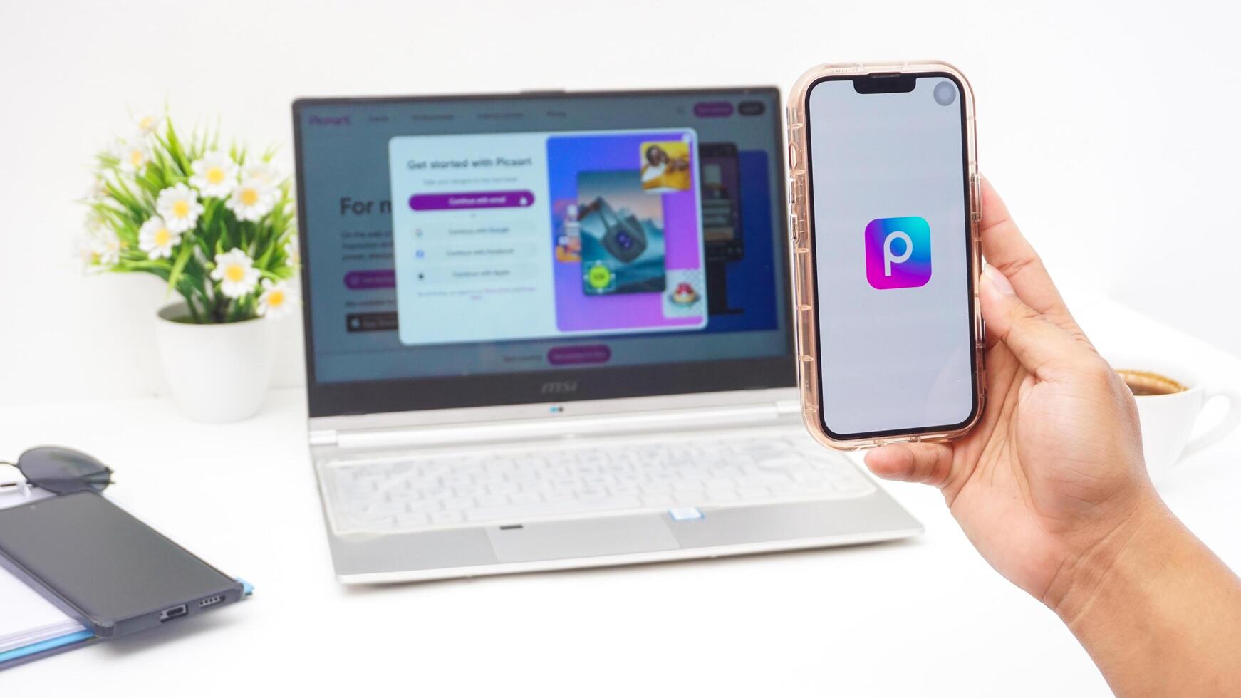 Yogyakarta, Indonesia, 2025 - Hand holding smartphone that shows front page of Picsart, a creative editing platform application on the screen isolated on white background photo