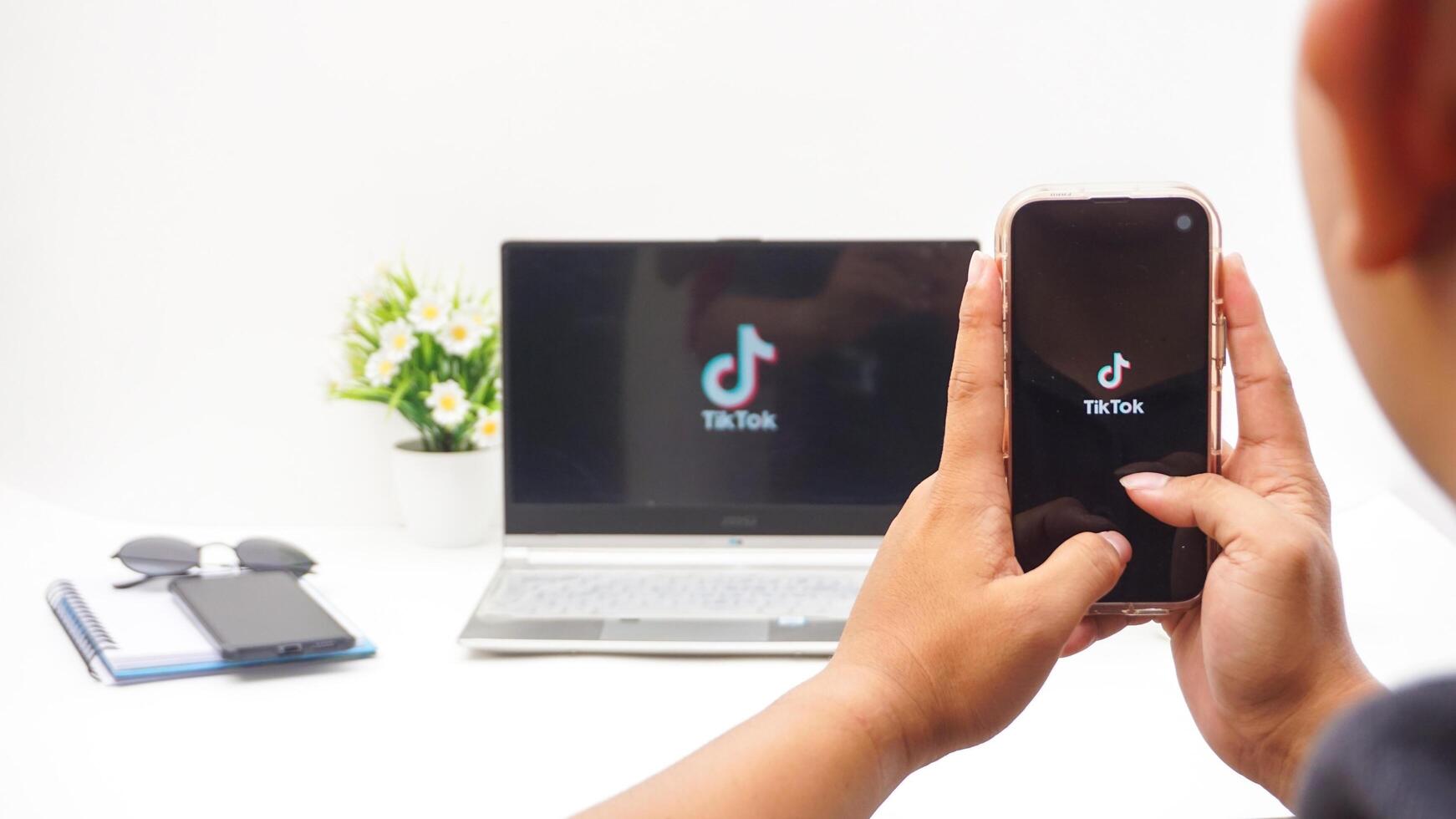 Yogyakarta, Indonesia, 2025 - Man with smartphone that shows front page of Tiktok, social and entertainment platform application on the screen isolated on white background photo