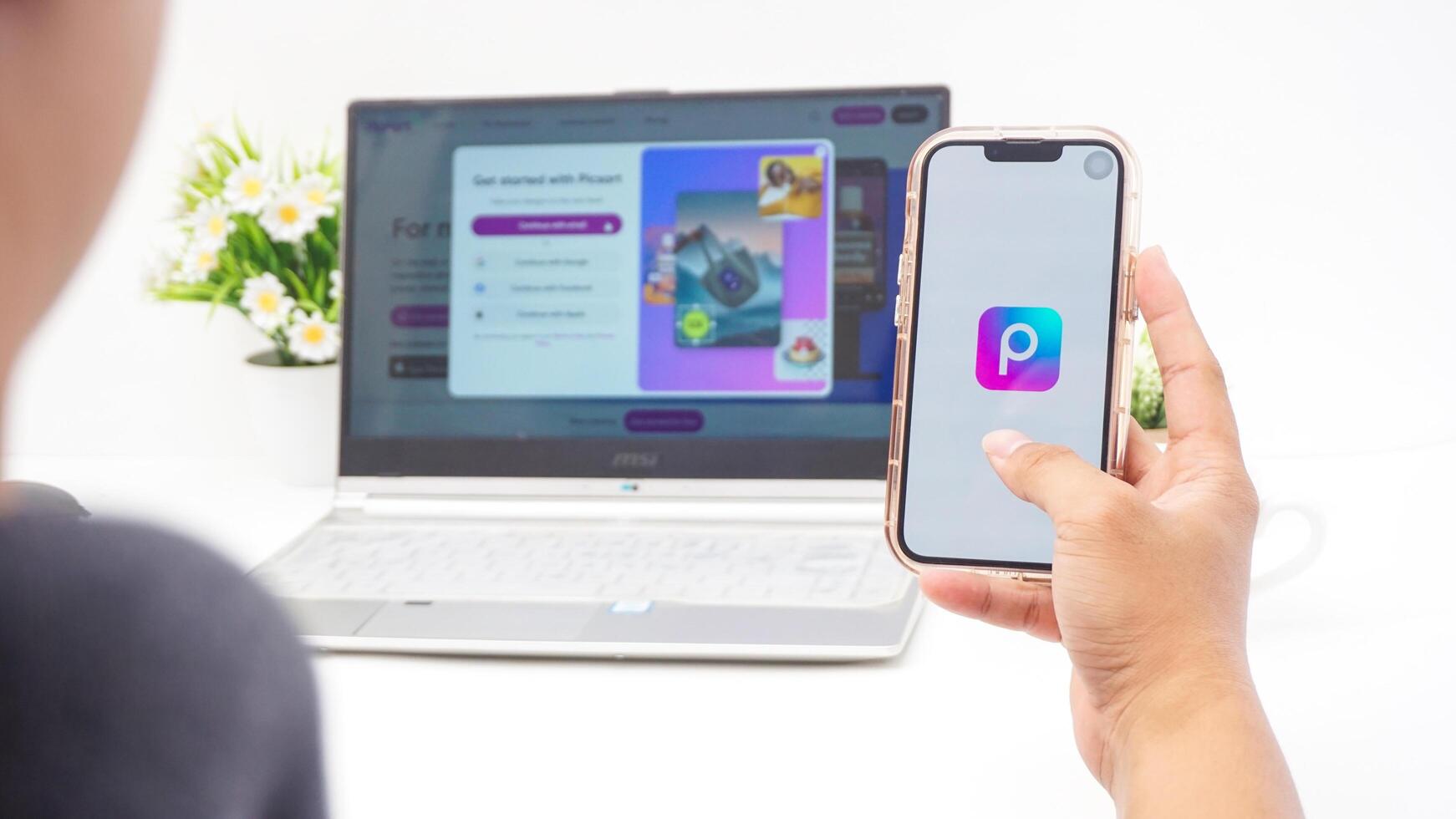 Yogyakarta, Indonesia, 2025 - Man holding smartphone that shows front page of Picsart, a creative editing platform application on the screen isolated on white background photo