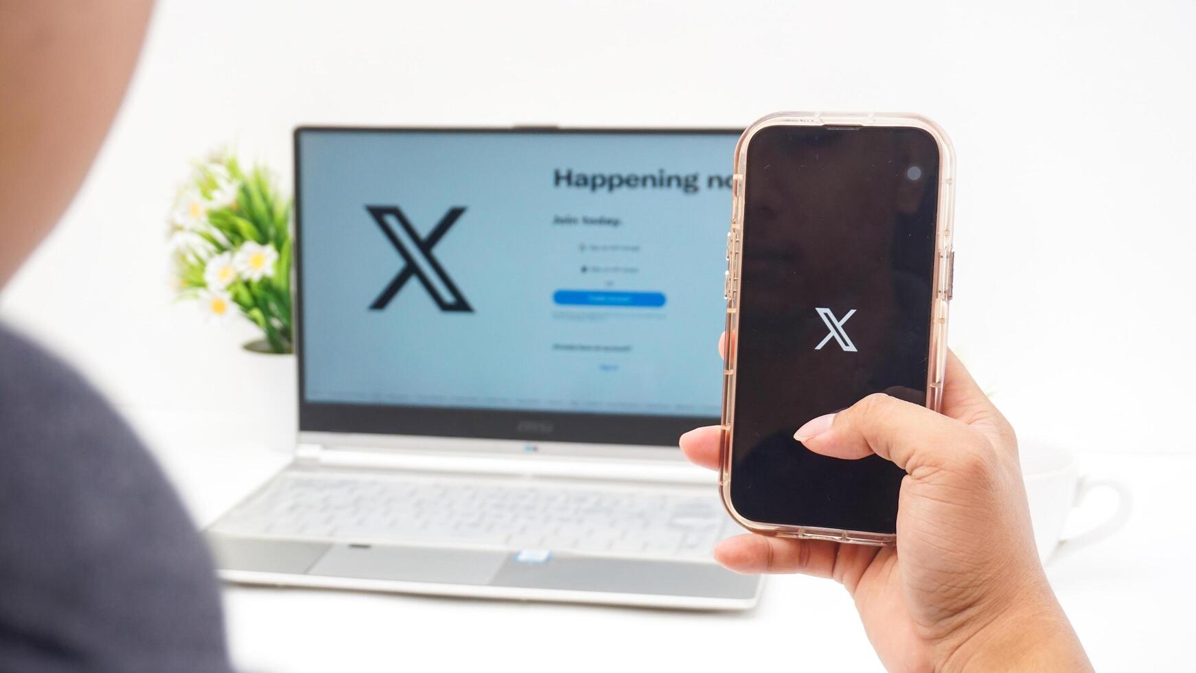Yogyakarta, Indonesia, 2025 - Hand holding smartphone that shows icon of X application former Twitter, social media platform on the screen isolated on white background photo