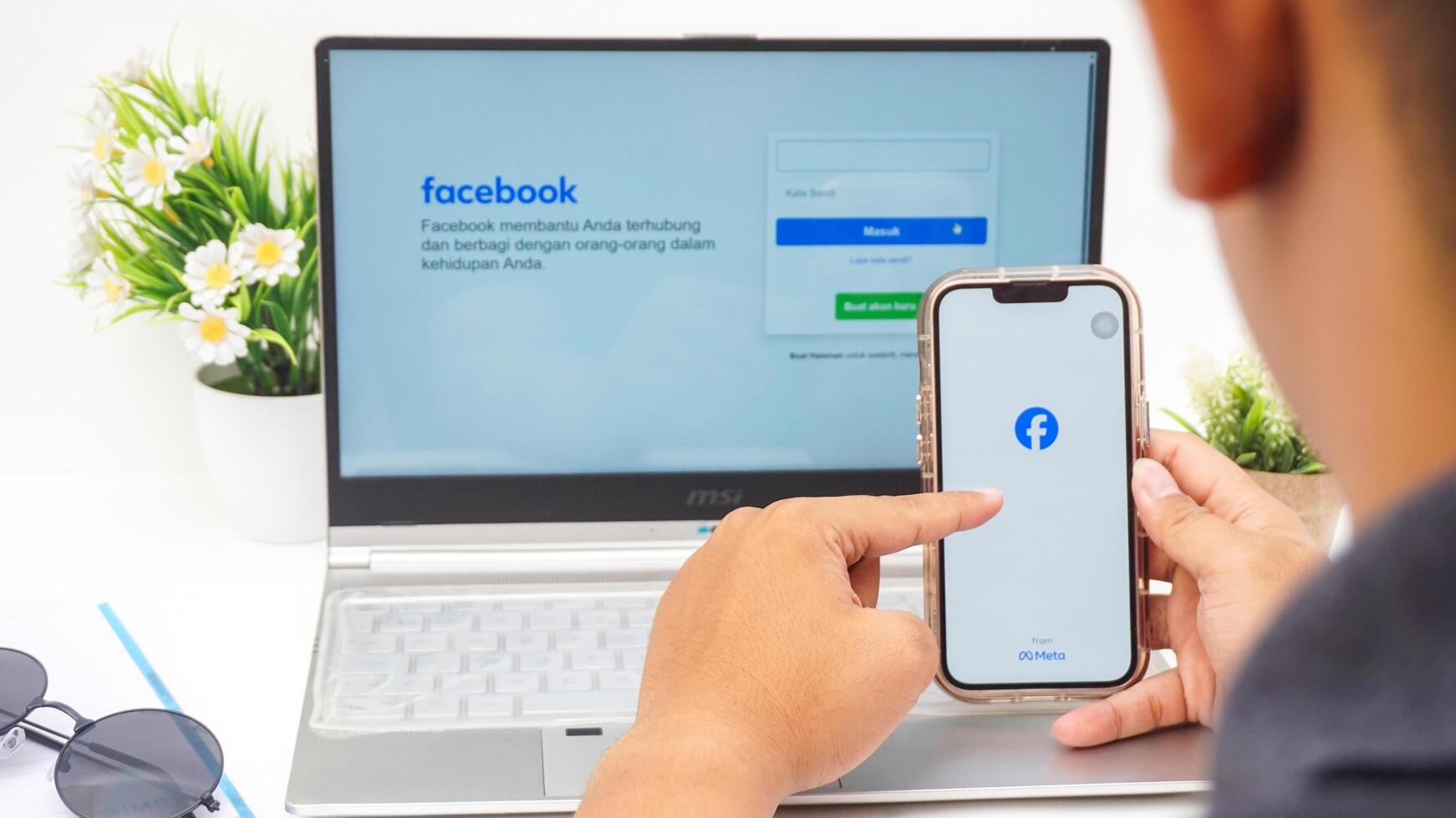 Yogyakarta, Indonesia, 2025 -Man using smartphone that shows front page of Facebook, social networking service application on the screen isolated on white background photo