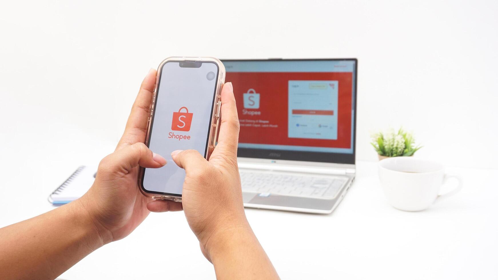 Yogyakarta, Indonesia, 2025 - Hand with smartphone that shows front page of Shopee, e-commerce or online shopping platform application on the screen isolated on white background photo