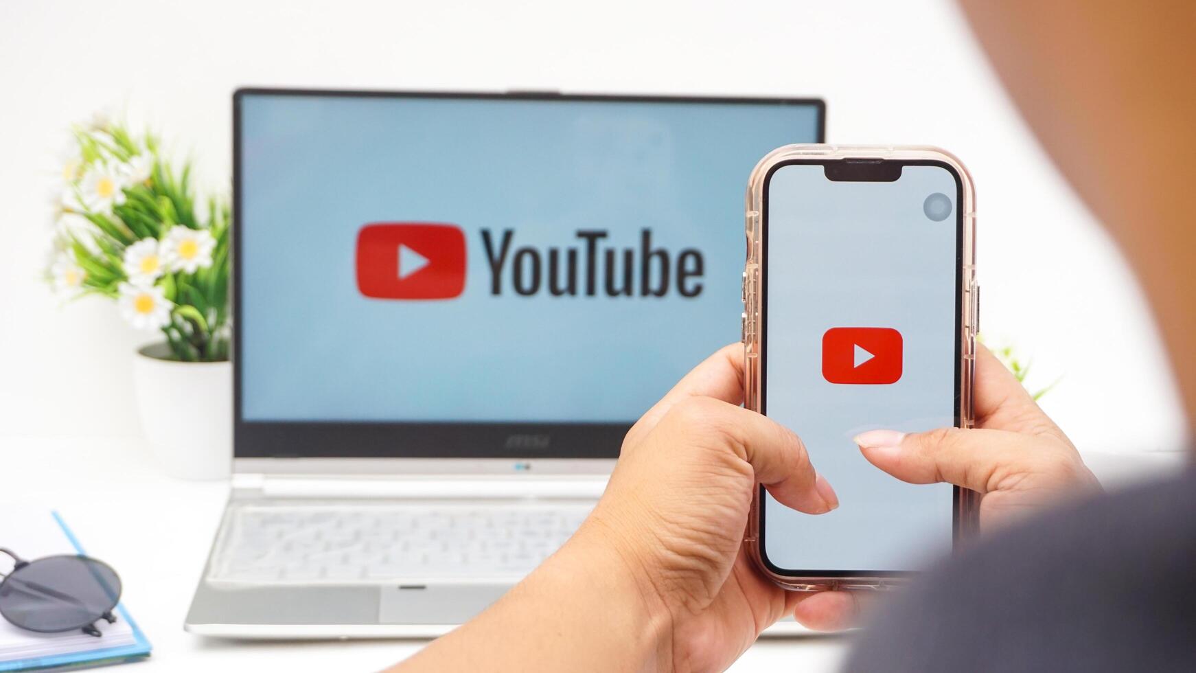 Yogyakarta, Indonesia, 2025 - Man holding smartphone that shows front page of Youtube platform application on the screen isolated on white background photo