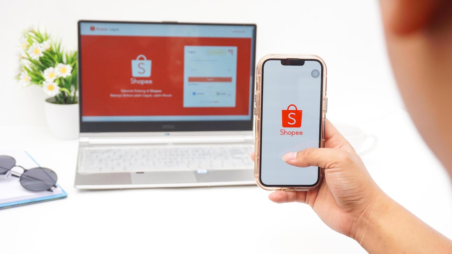 Yogyakarta, Indonesia, 2025 - Man holding smartphone that shows front page of Shopee, e-commerce or online shopping platform application on the screen isolated on white background photo