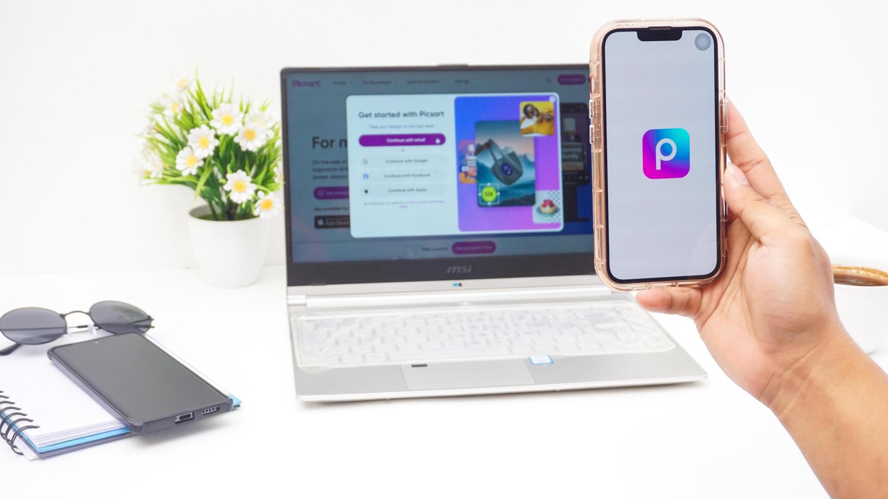 Yogyakarta, Indonesia, 2025 - Hand with smartphone that shows front page of Picsart, a creative editing platform application on the screen isolated on white background photo
