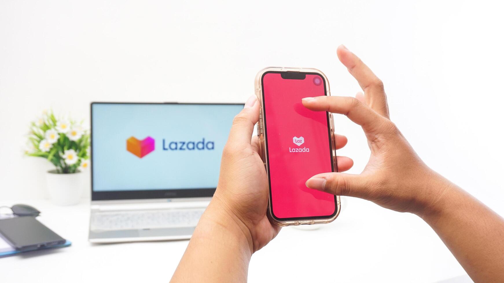 Yogyakarta, Indonesia, 2025 - Man hand holding smartphone that shows front page of Lazada e-commerce platform application on the screen isolated on white background photo