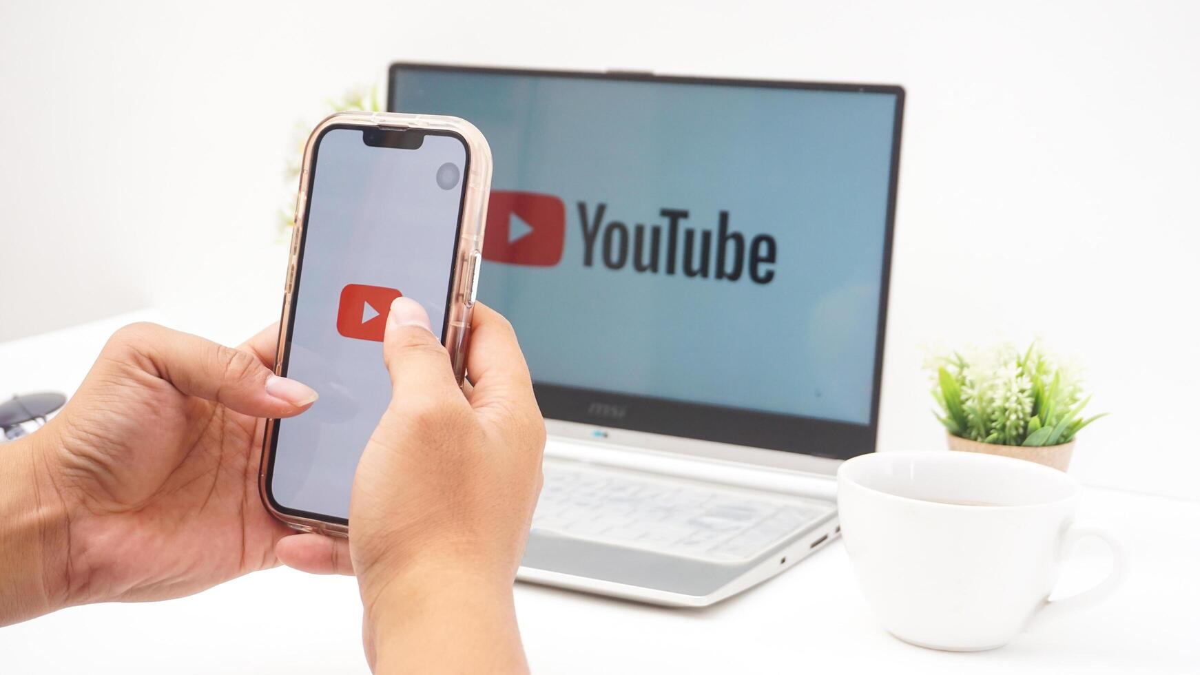 Yogyakarta, Indonesia, 2025 - Hand with smartphone that shows icon of Youtube platform application on the screen isolated on white background photo