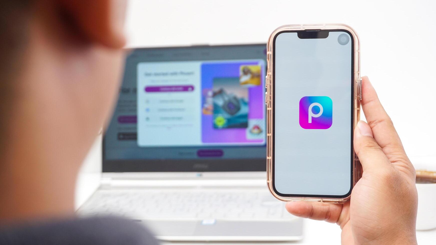 Yogyakarta, Indonesia, 2025 - Man with smartphone that shows front page of Picsart, a creative editing platform application on the screen isolated on white background photo