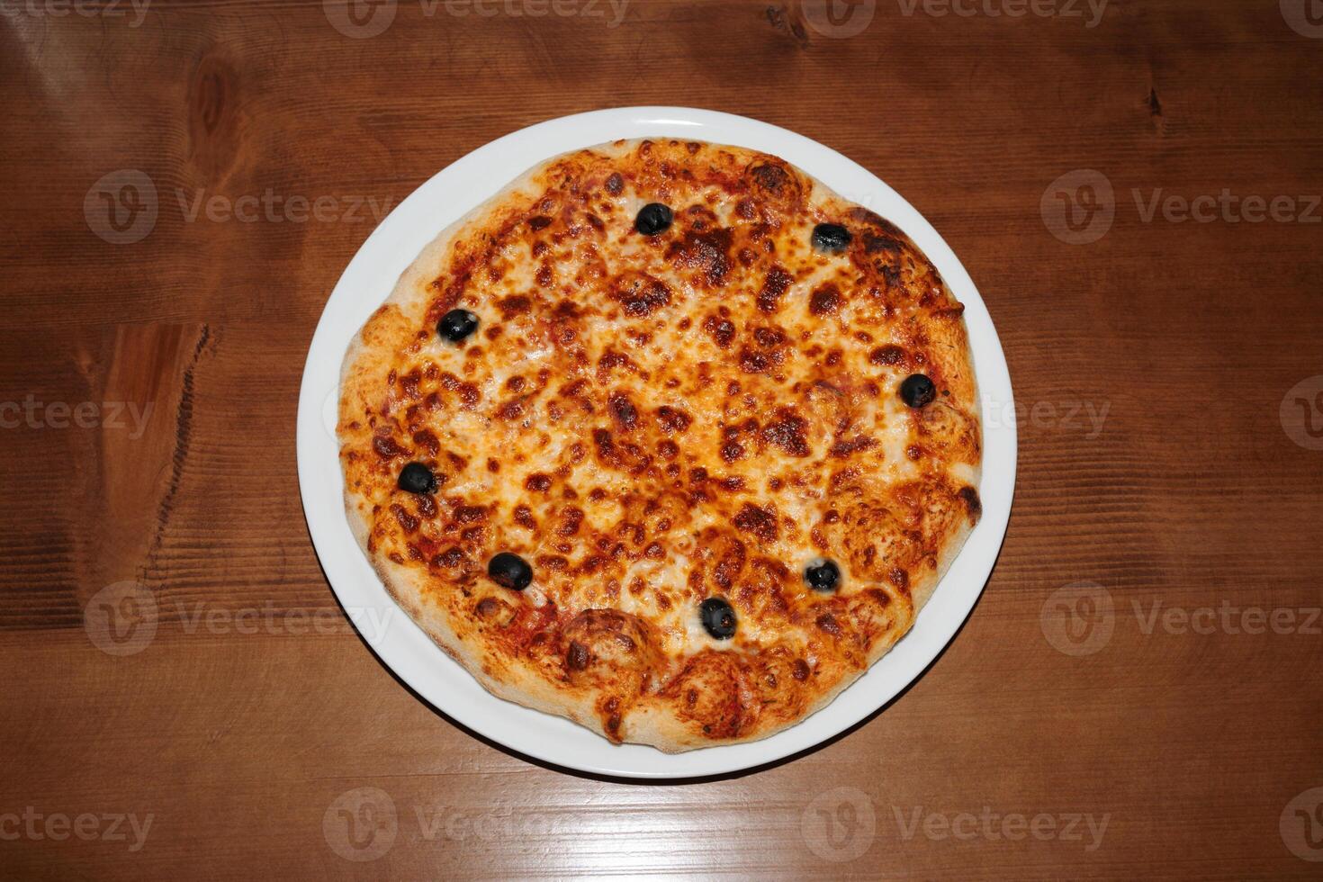 Cheese olive pizza on wooden background. Retro flash food photography photo