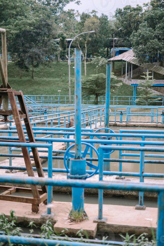 Water treatment facility detail with blue metal structures and greenery photo