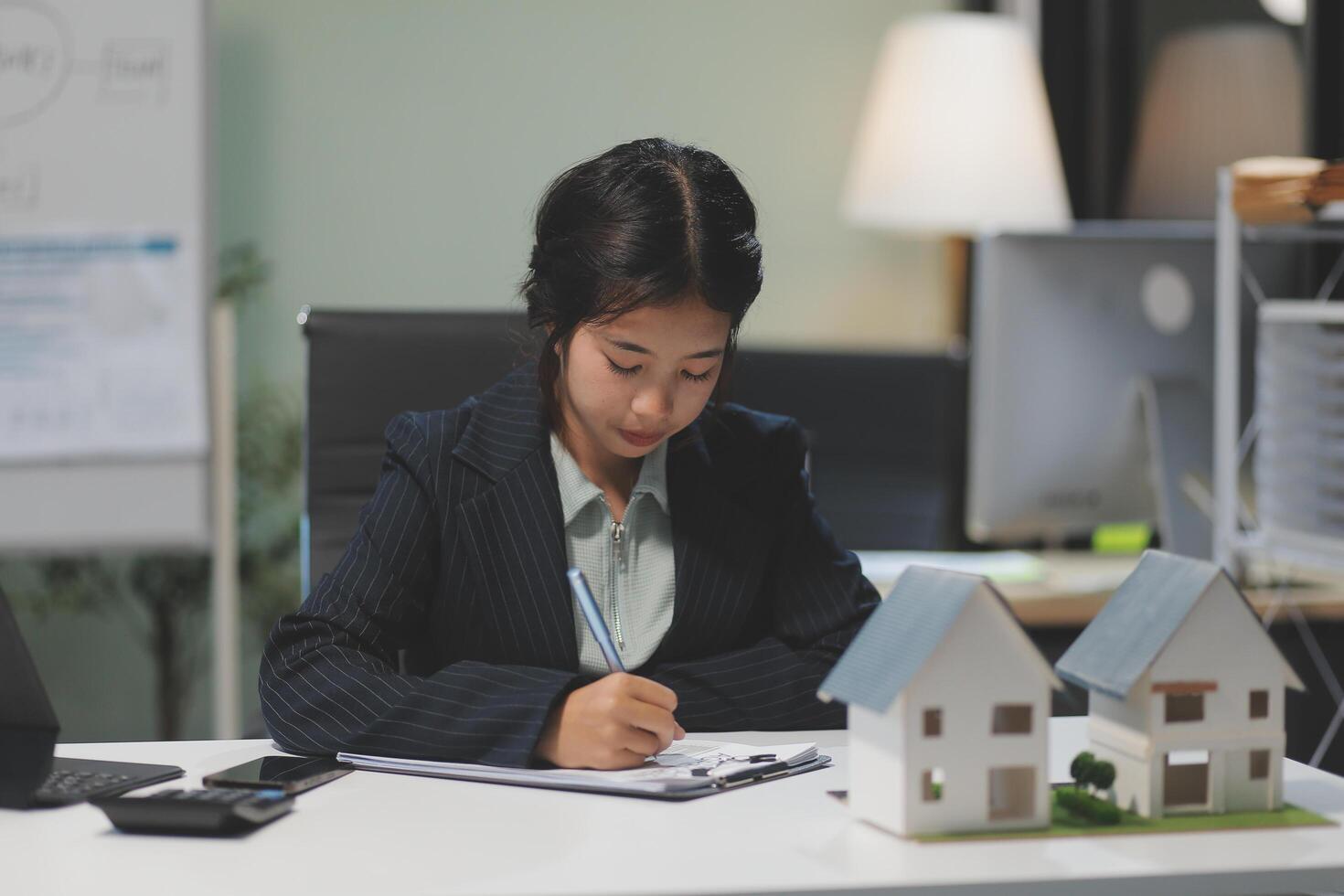 A woman in a business suit writing on a piece of paper photo