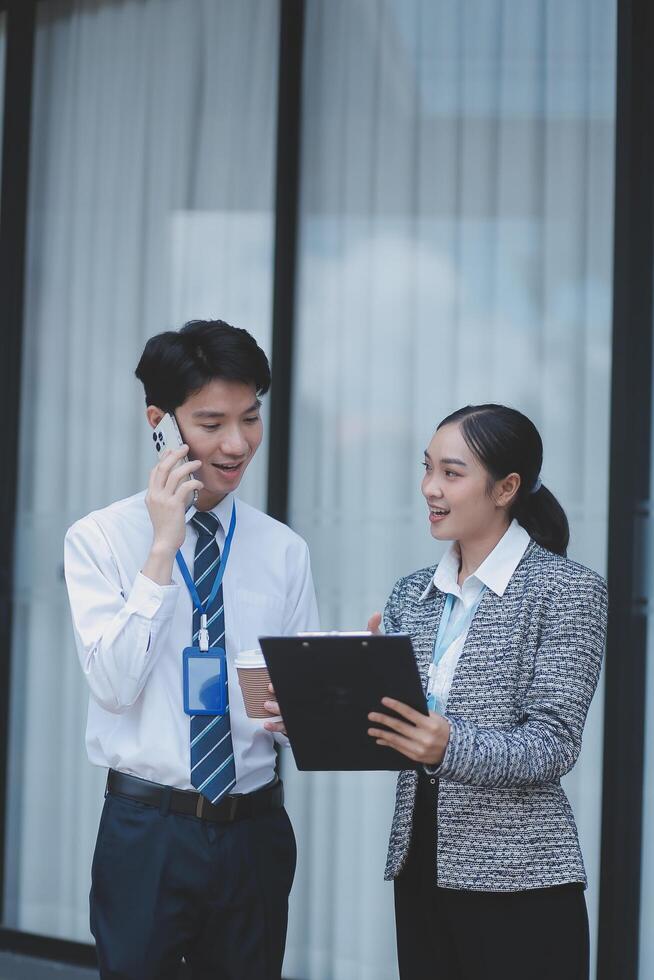 Two business people standing next to each other talking on a cell phone photo