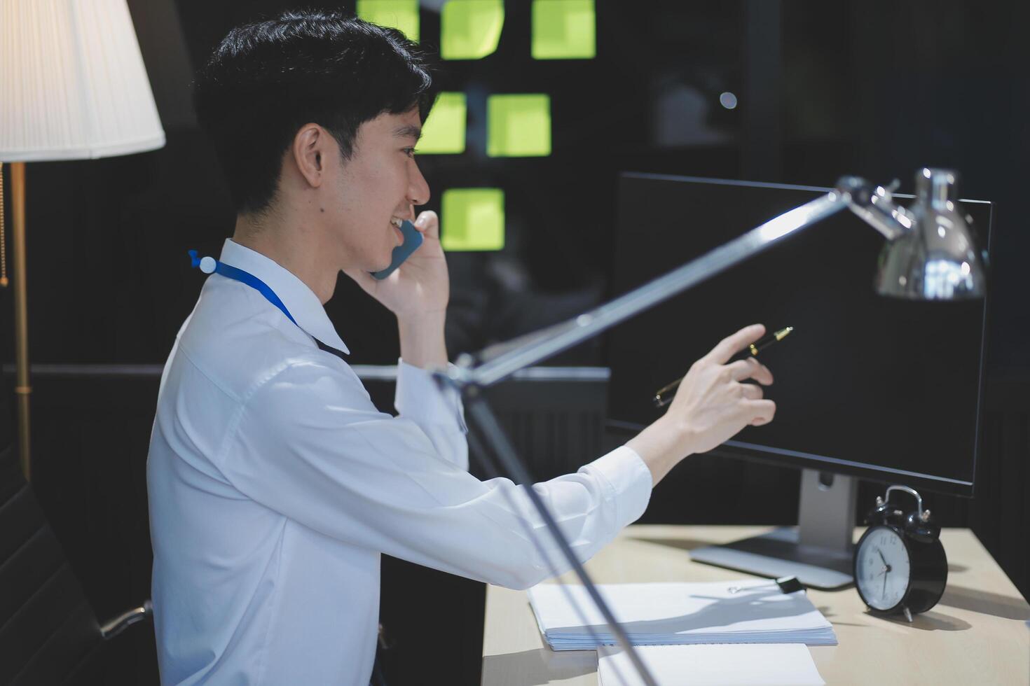 A man sitting at a desk with a computer and a phone photo