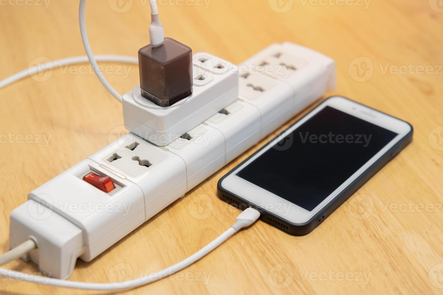 Mobile phones charging into power cord on wooden floor indoors. photo