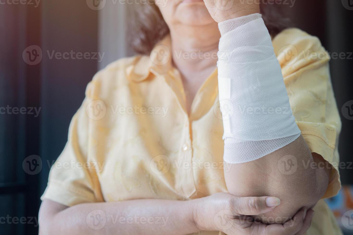 Shot of older Asian woman with gauze bandage wrapped around her arm. photo