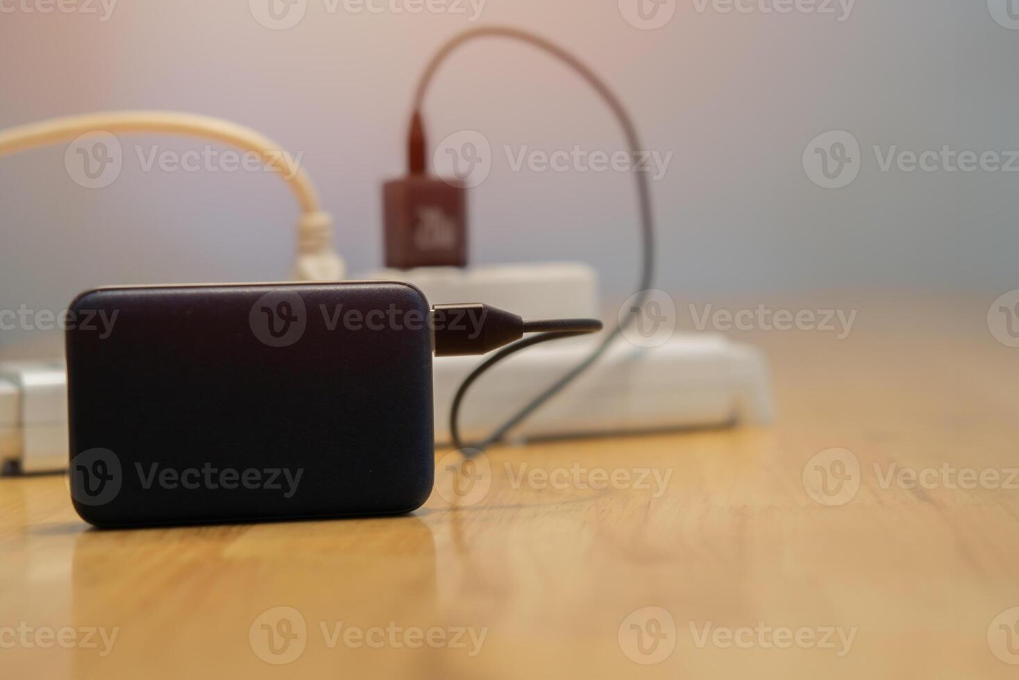 Extension cord with charging gadgets on wooden table at home. Close up photo