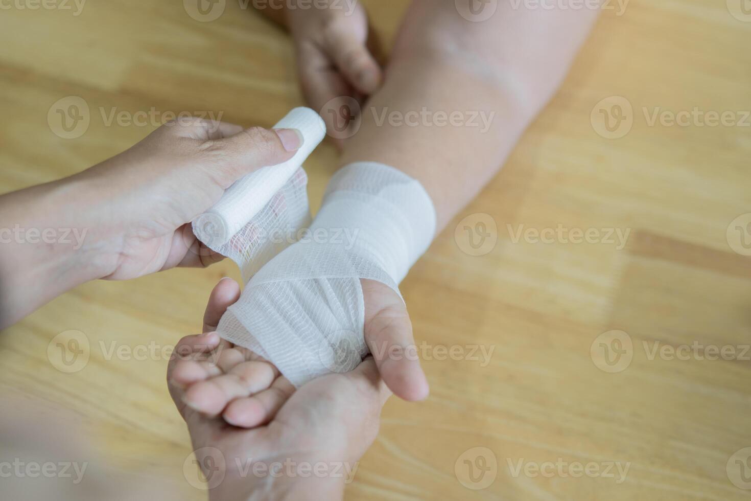 Close up of young female bandaging a white medicine bandage on old female hand. photo