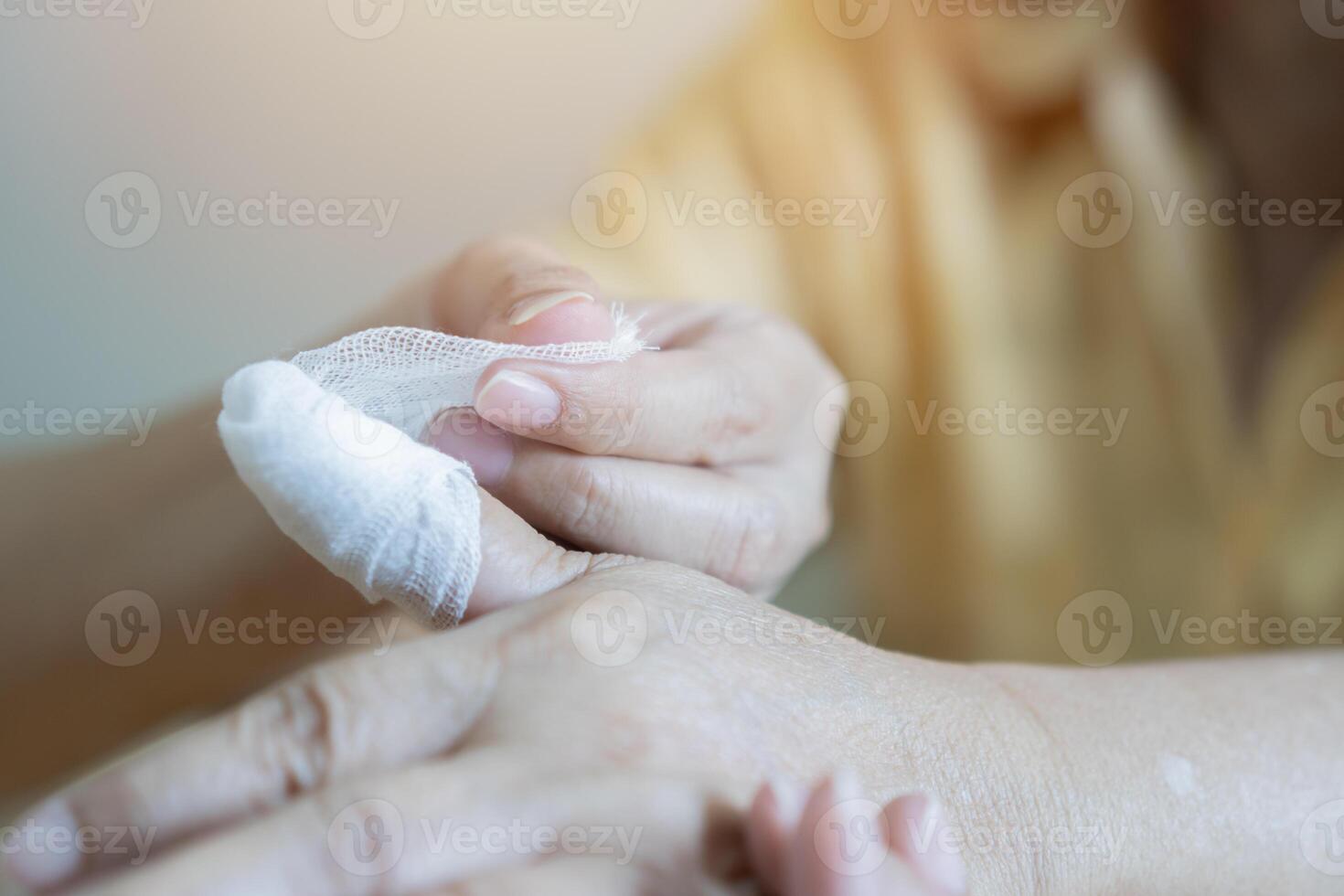 Emergency concept. Doctor applying bandage onto finger of old woman. photo