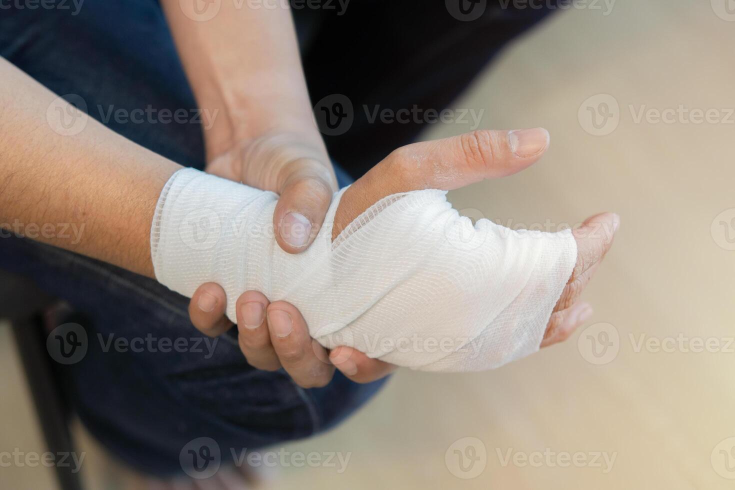 Wrapping wrist and arm with bandage around injured man's hand at home. First aid photo