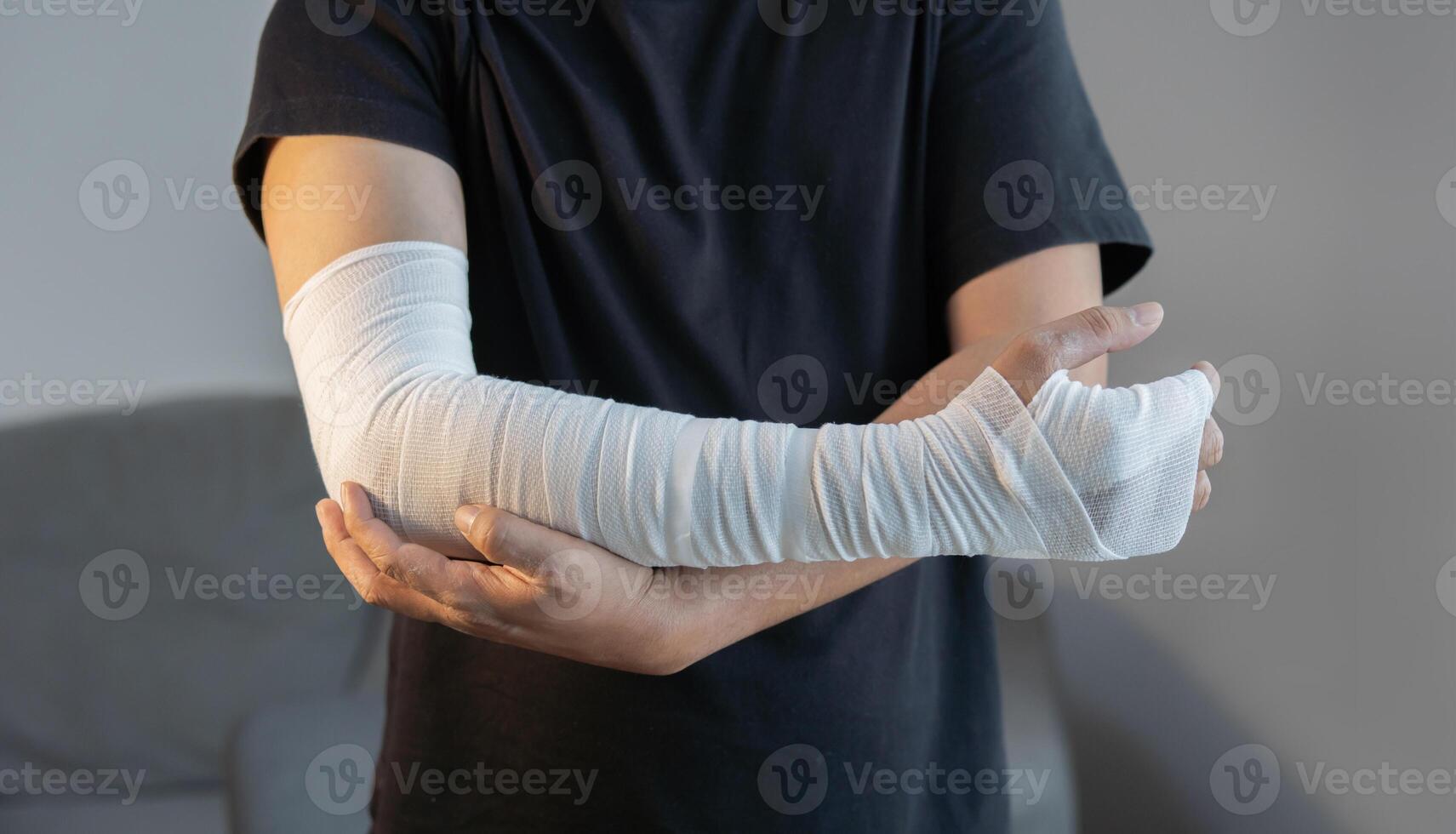 Cropped image of adult man with gauze bandage wrapped around his injured arms, hand at home. photo