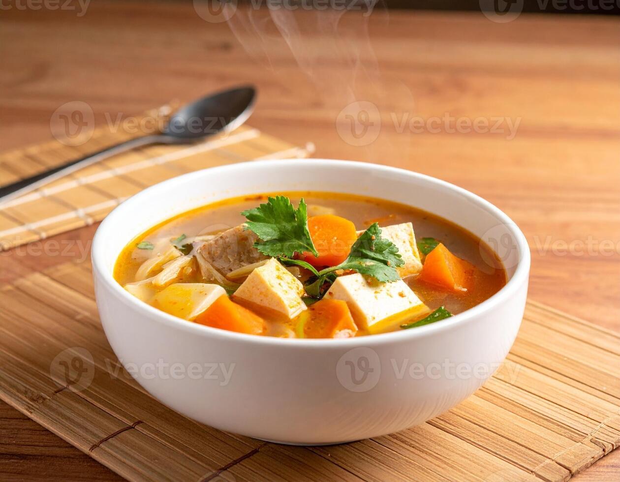 Hot and Sour Soup with Tofu and Vegetables in a Steaming White Bowl photo