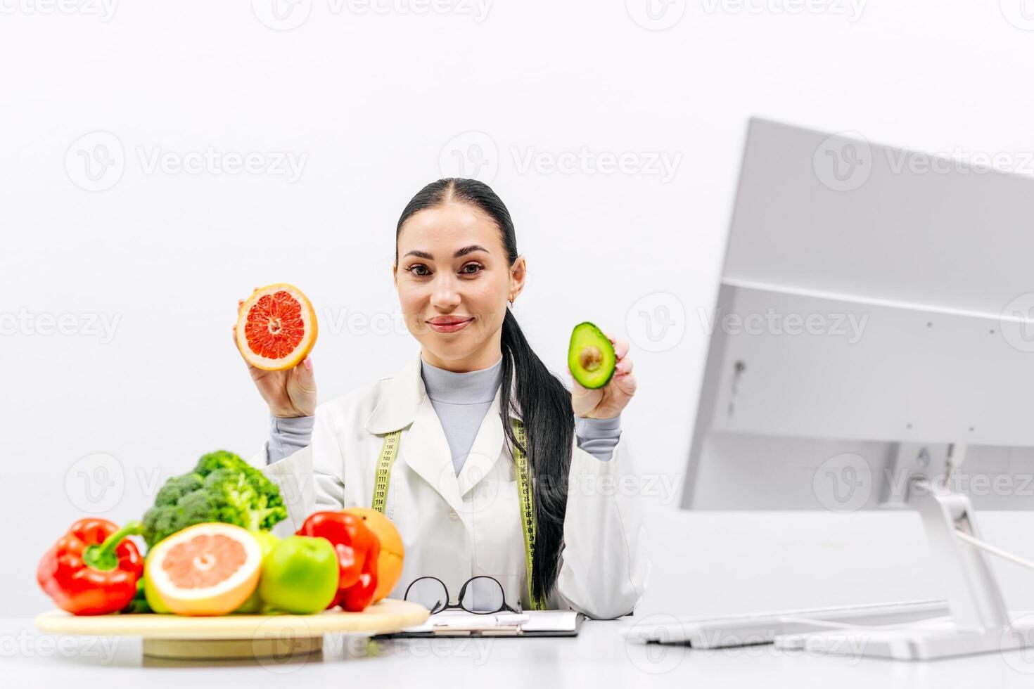 Choose quality healthy food. Cheerful female nutritionist holding fresh fruits and vegetables, smiling at camera at clinic. Weight loss consultant recommending healthy plant based diet photo