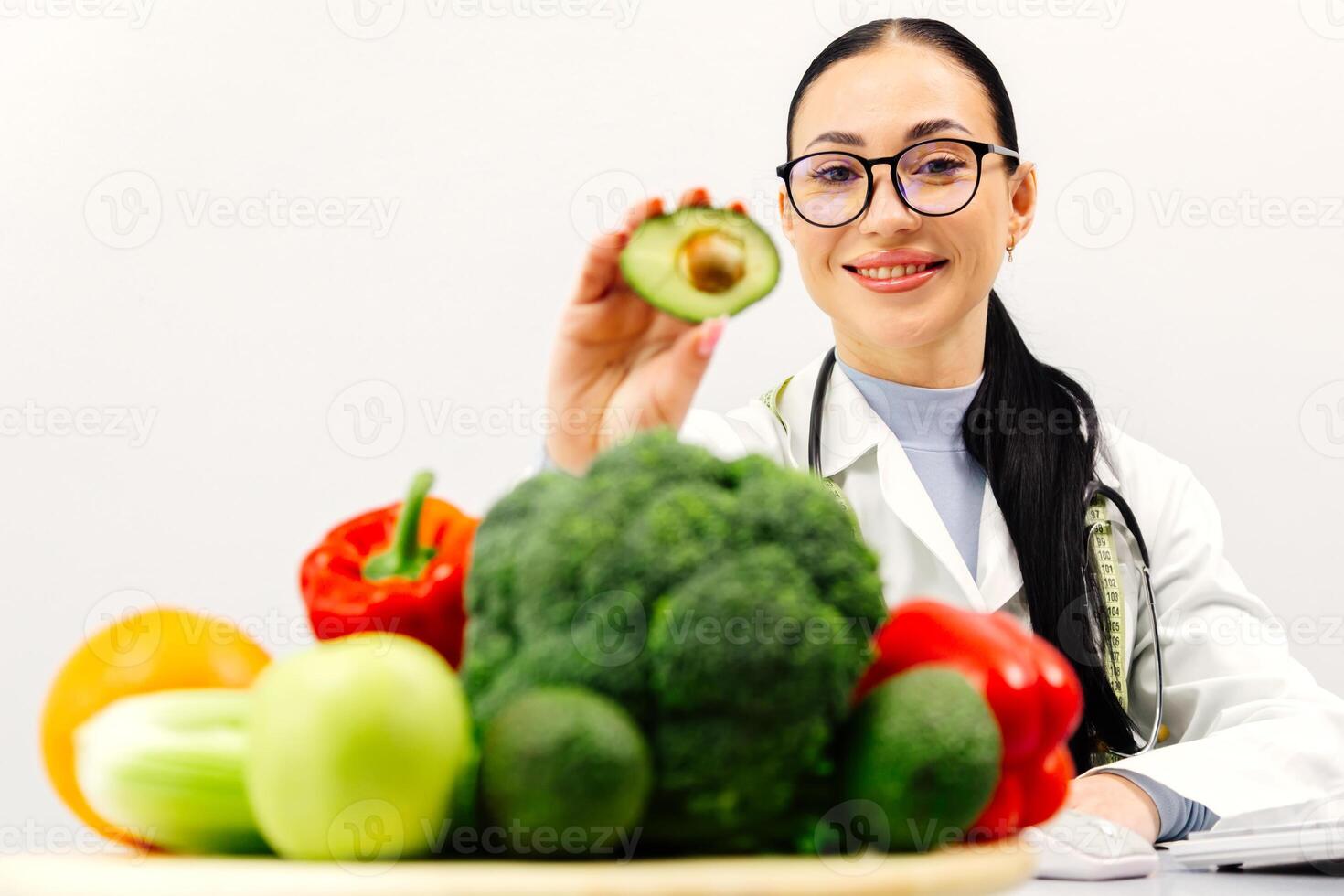 Female nutritionist working in a modern clinic on a light background with fresh vegetables and fruits. Concept of healthy eating, vegetarianism and weight loss photo