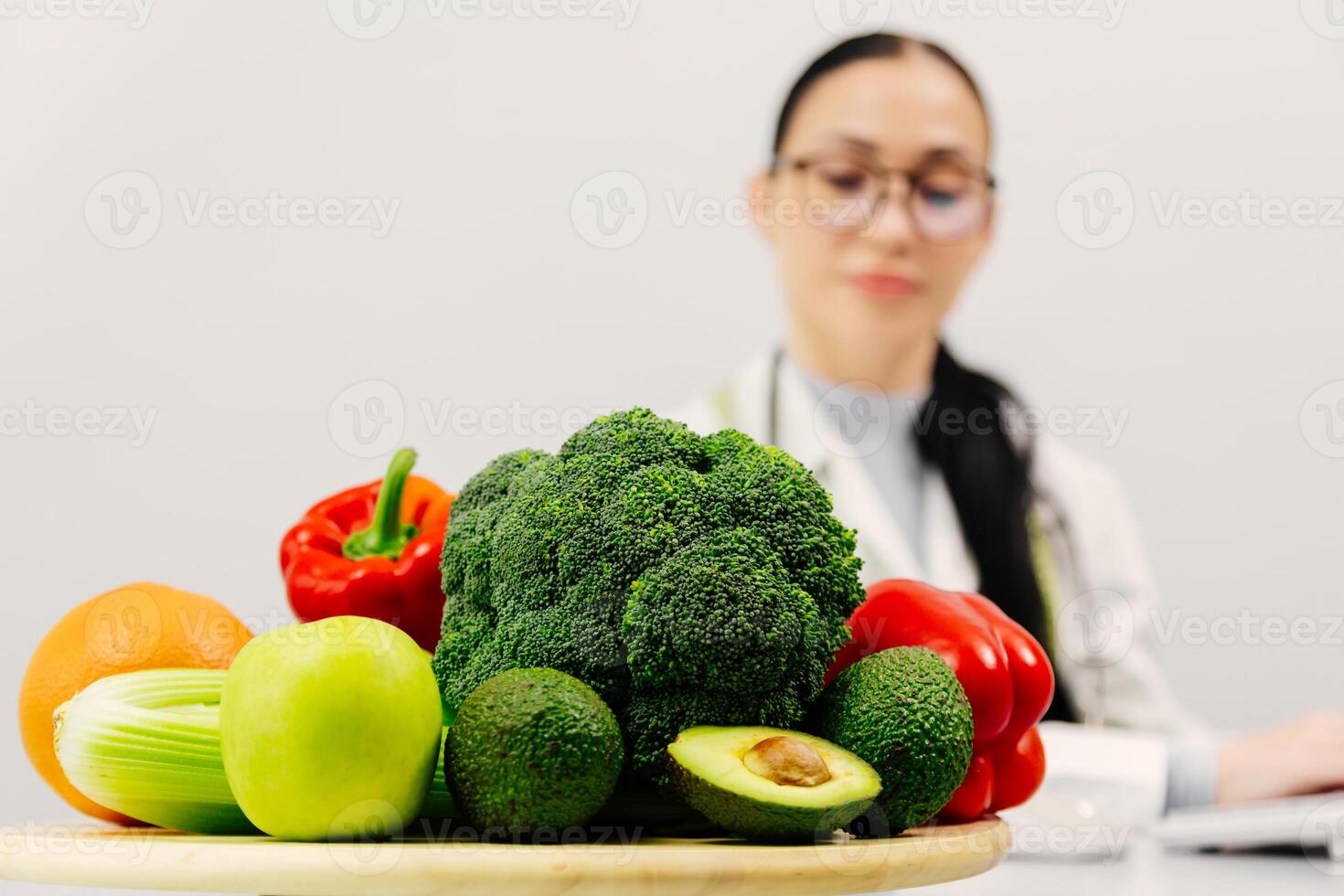 Shot of beautiful smart nutritionist woman working with computer while taking notes. Nutritionist consultation. Fresh vegetables and fruits are on the table. The concept of healthy eating. Copy space photo
