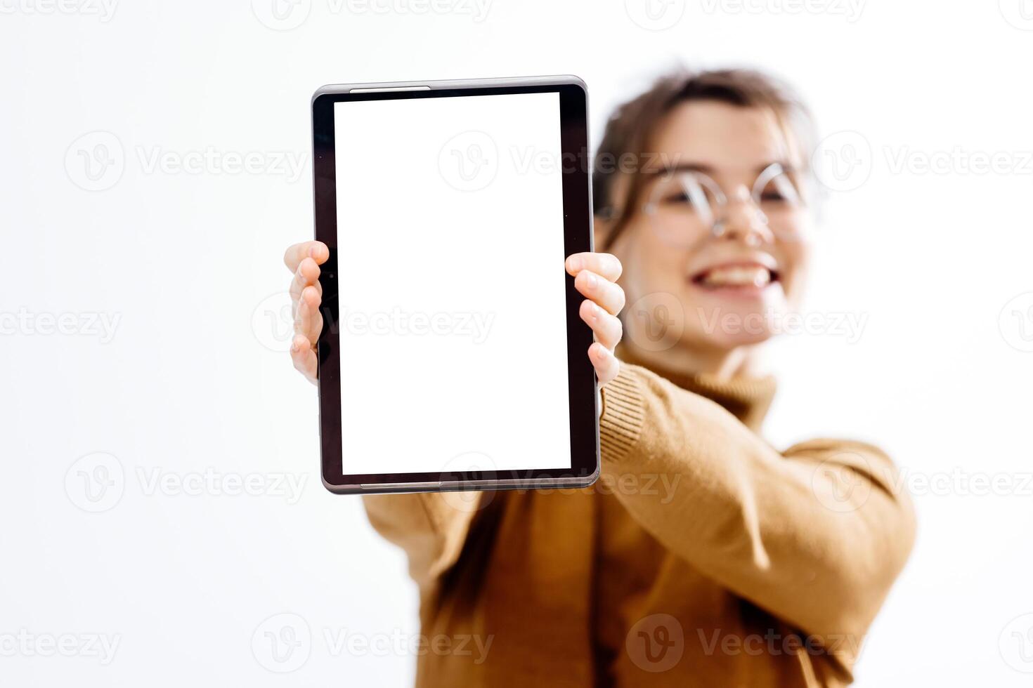 A young beautiful employee wearing glasses, smiling and holding a digital tablet with a white screen for your advertisement. White background, copy space photo