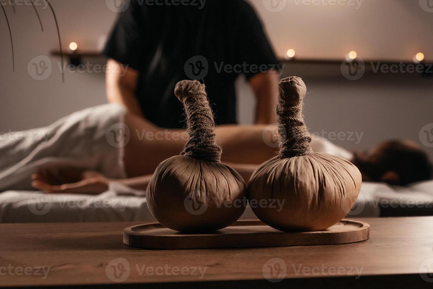 Thai Massage, asian woman in spa. Female having massage with herbal compress balls in therapy spa salon. Blurred background. Close-up compress balls on a table with candles. Advertising, copy space photo