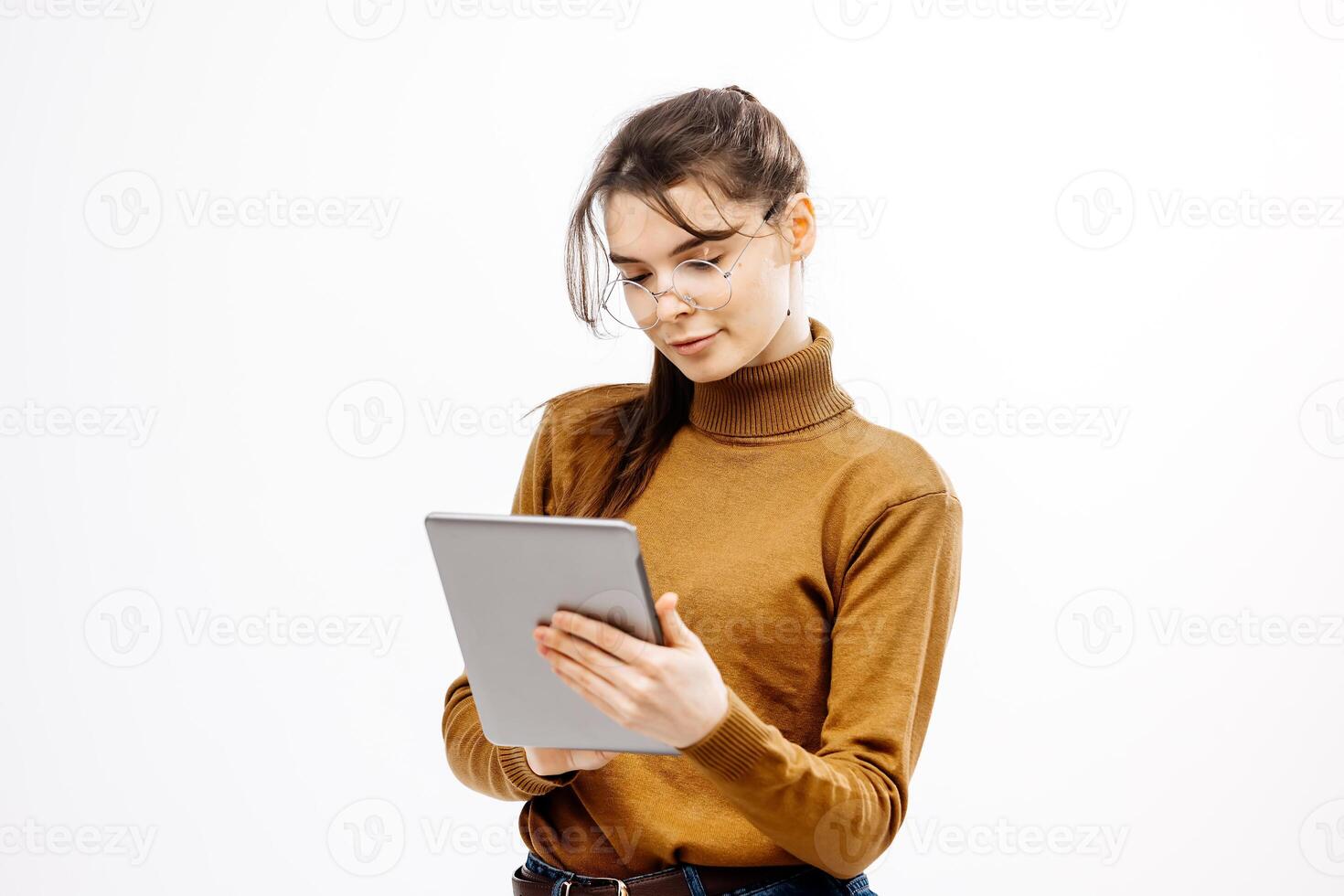 Concentrated Young Female Student Engaged digital tablet in glasses isolated on white background. Typing Notes and Studying Online. Free copy space. Education, technologies photo