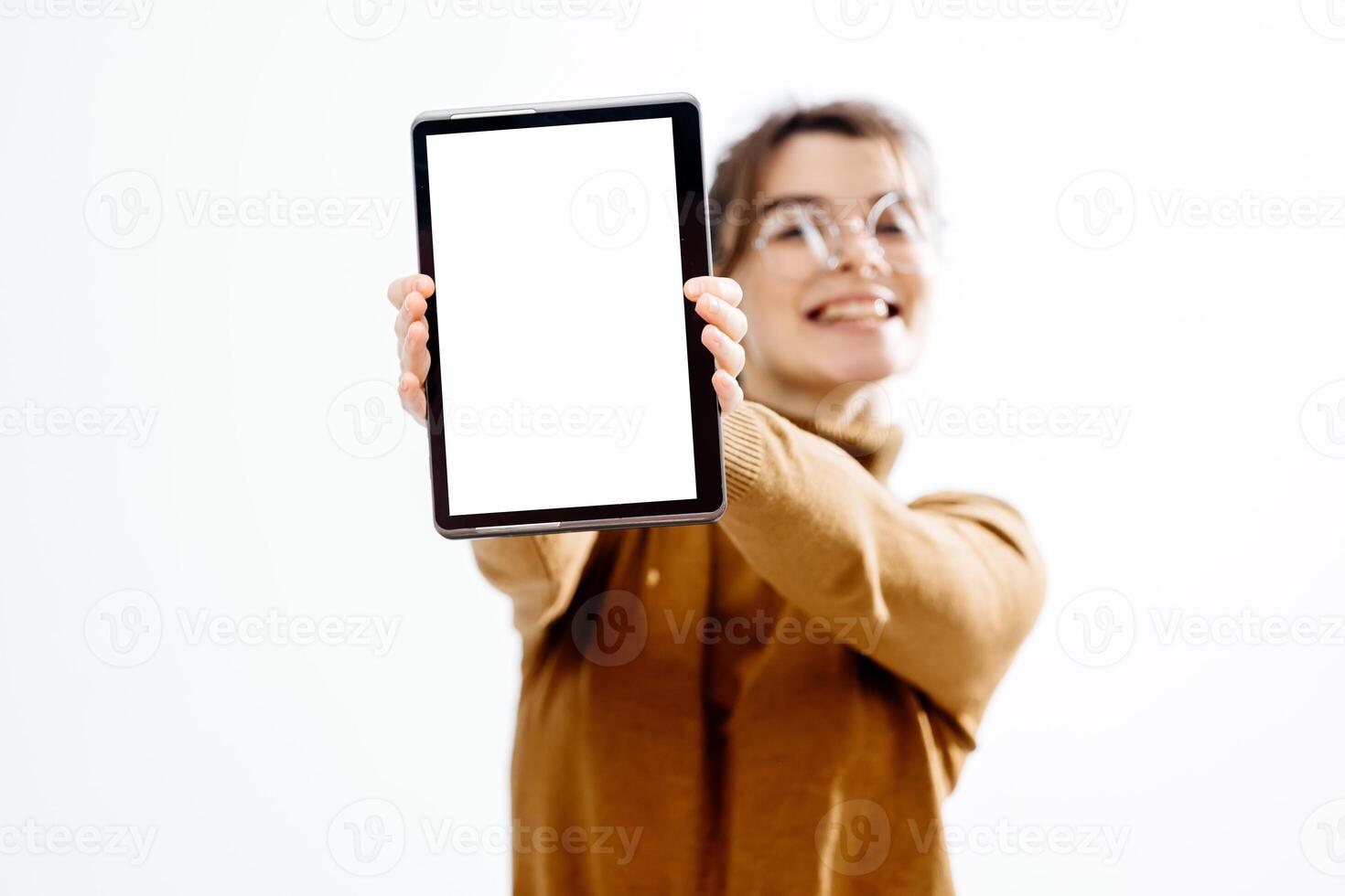 A young beautiful employee wearing glasses, smiling and holding a digital tablet with a white screen for your advertisement photo