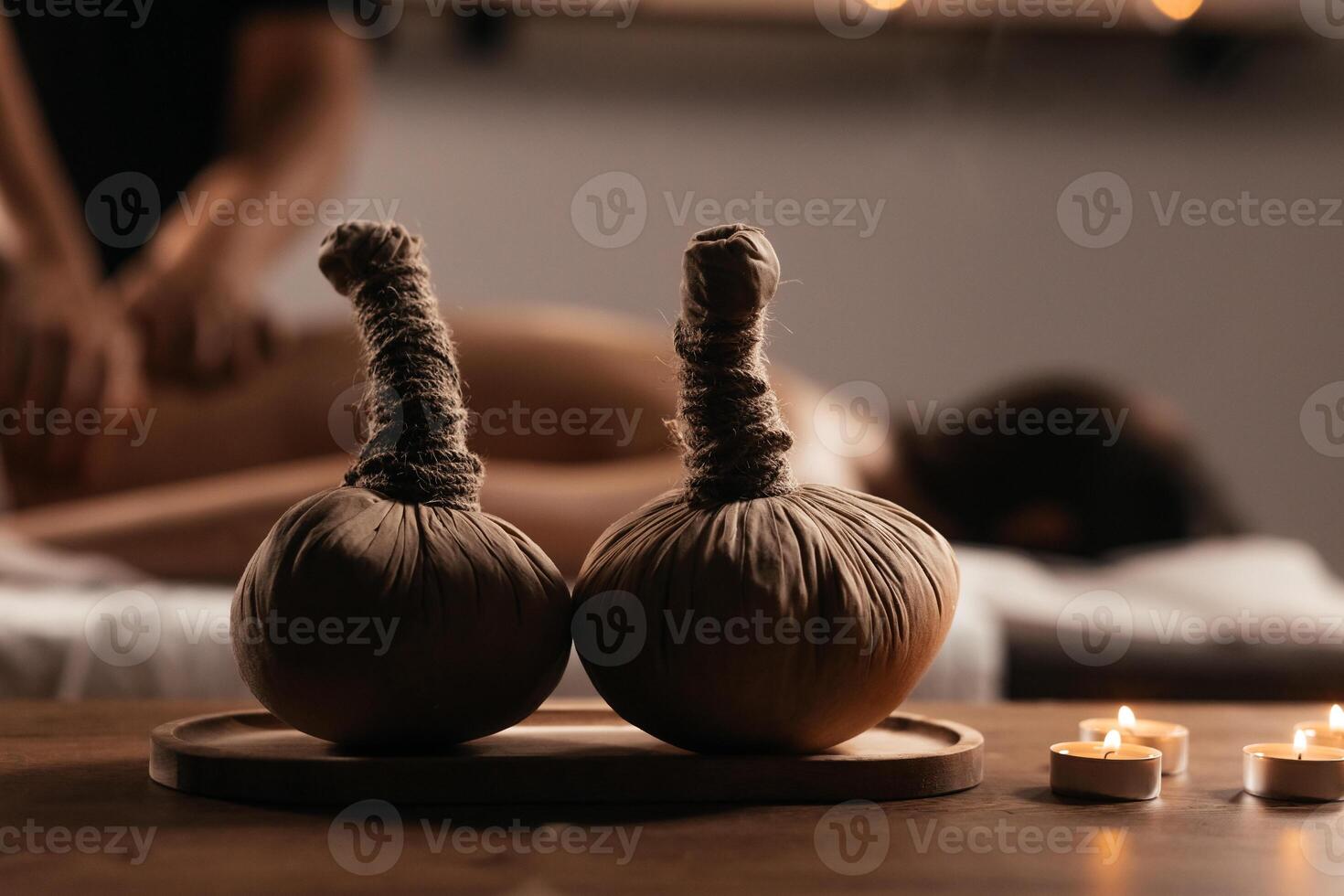 Thai Massage, asian woman in spa. Female having massage with herbal compress balls in therapy spa salon. Blurred background. Close-up compress balls on a table with candles. Banner, copy space photo
