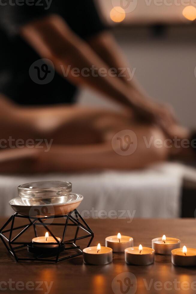 Relaxed woman lying on massage table while massage therapist massages her back, applying pressure to release tension in the woman muscles. Authentic shot of luxury spa treatment. Vertical background photo