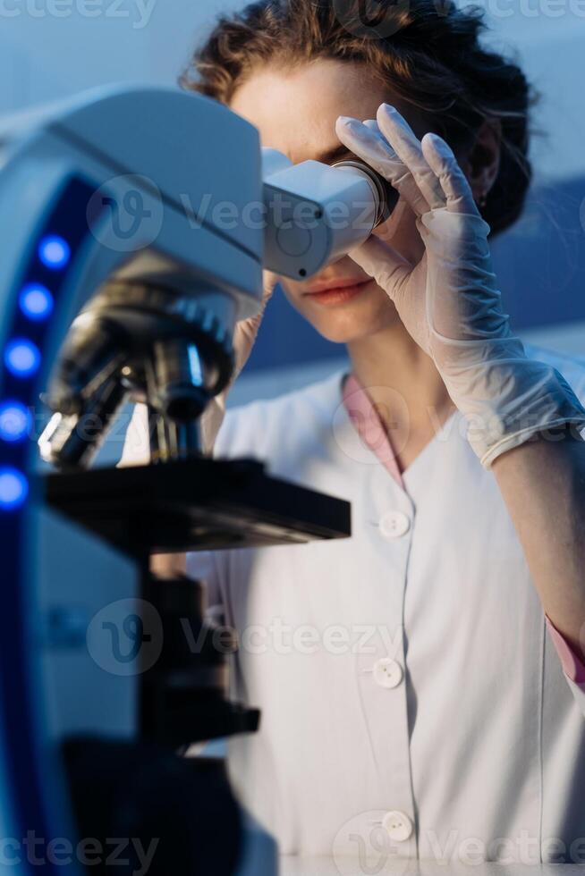 Scientist using microscope in laboratory. Close-up of a researcher hands adjusting a modern microscope in a lab setting. Serious concentrated female microbiologist. Science concept. Vertical photo