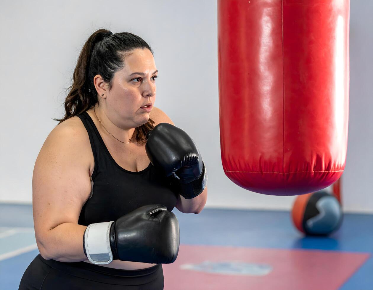 A plus-size woman practicing boxing with a coach using pads at a neighborhood gym, showing focus and effort. photo