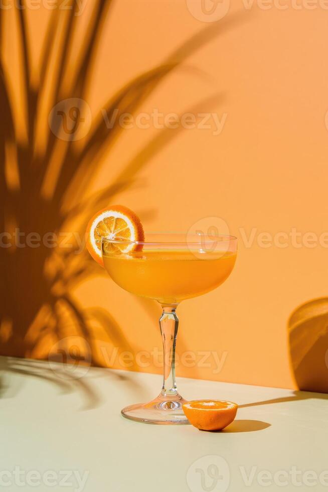 Bright cocktail on a table with orange background and playful shadows from plants photo