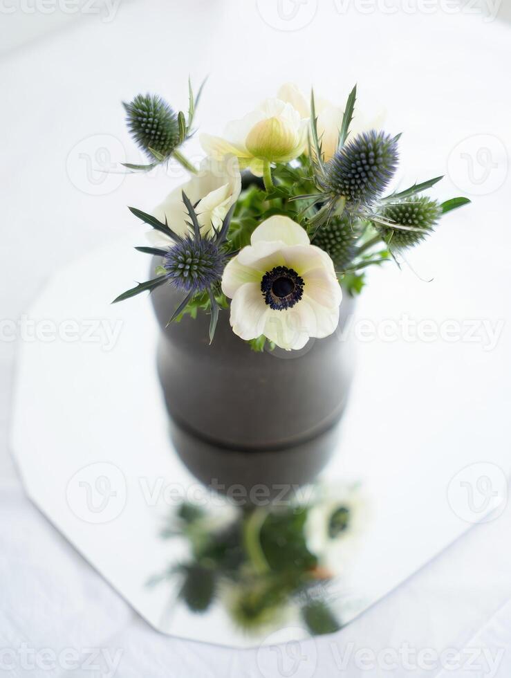 Beautiful floral arrangement in a modern vase on a reflective surface with natural light photo